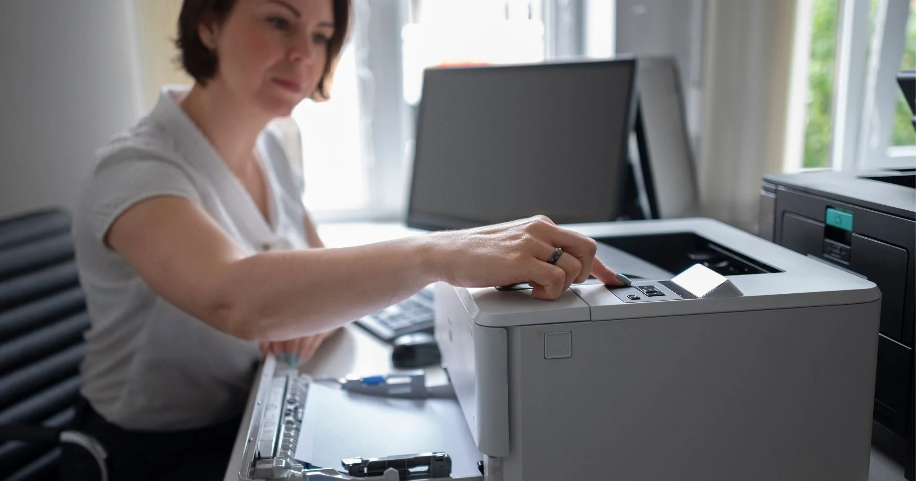 Office worker using desktop printer at workspace