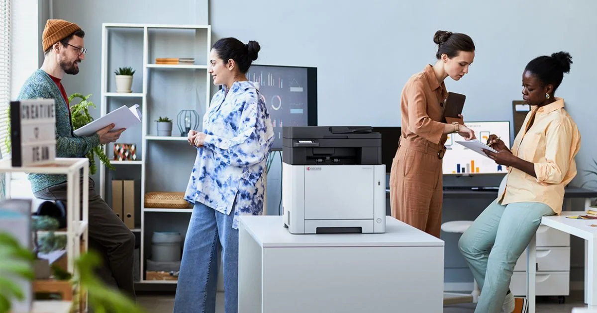 Office team collaborating around printer in modern workspace